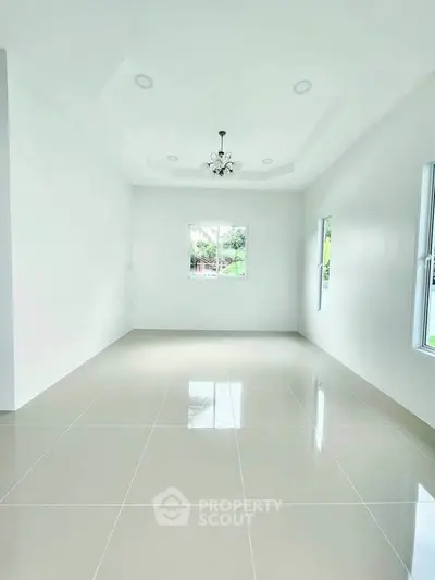 Spacious empty room with elegant chandelier and glossy tiled floor, perfect for customization.