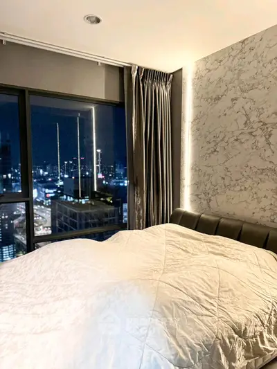 Luxurious bedroom with stunning city view and elegant marble accent wall.