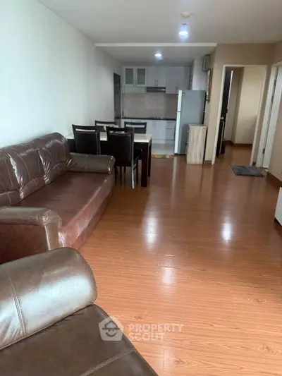 Spacious living room with leather sofas and dining area leading to a modern kitchen.