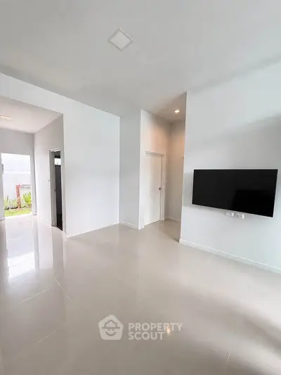 Spacious modern living room with sleek tile flooring and wall-mounted TV, perfect for contemporary living.