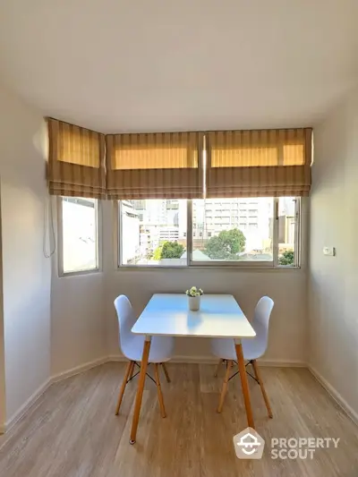 Bright dining nook with modern table and chairs, large windows, and city view.