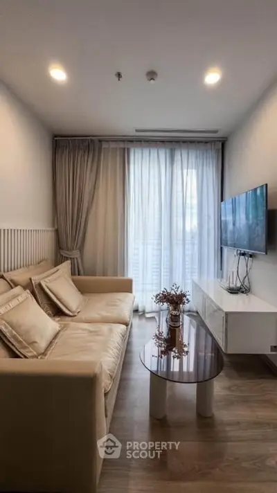 Cozy living room with modern decor, featuring a plush sofa, wall-mounted TV, and elegant curtains.