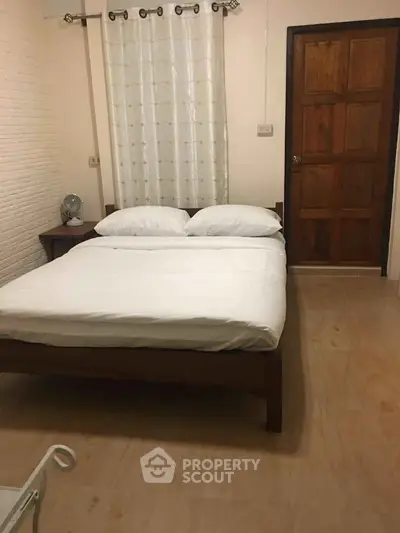Cozy bedroom with wooden bed frame and white bedding, perfect for relaxation.