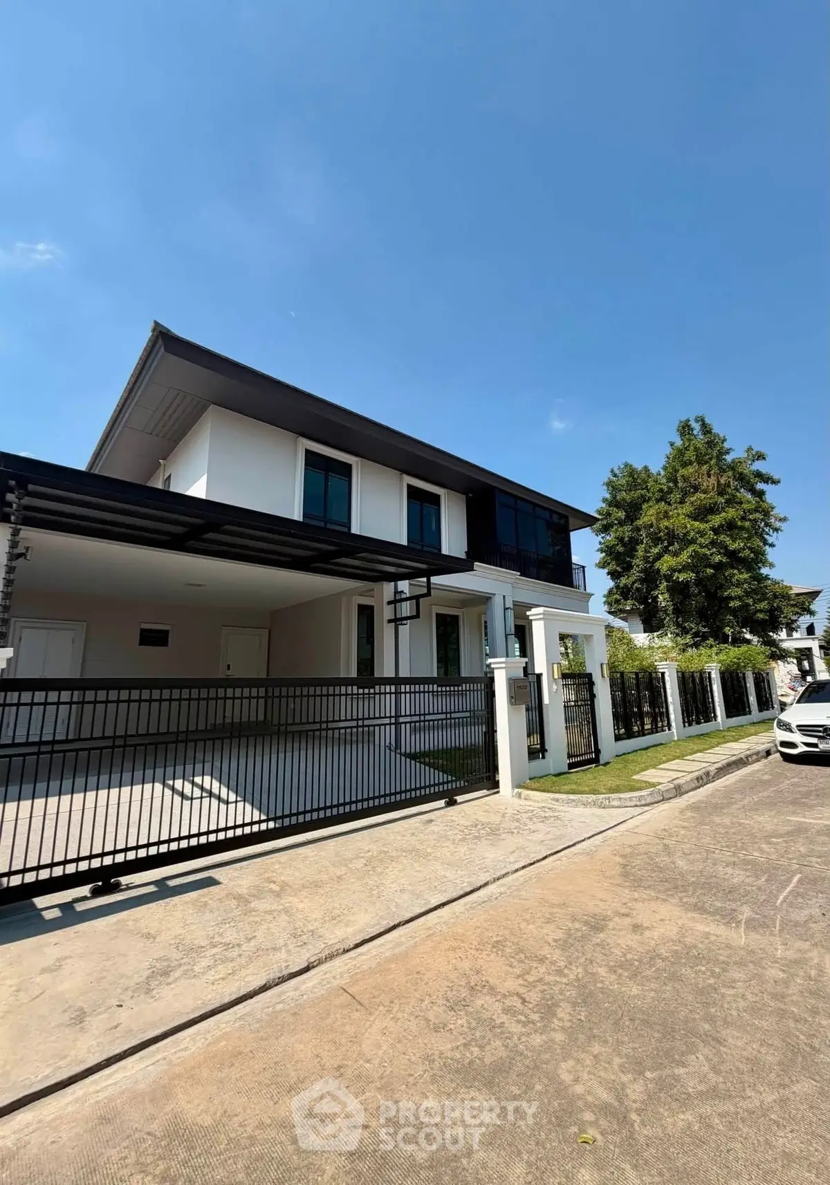 Modern two-story house with sleek design and spacious driveway in a serene neighborhood.