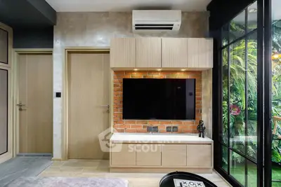 Modern living room with stylish TV setup and garden view, featuring sleek air conditioning and natural light.