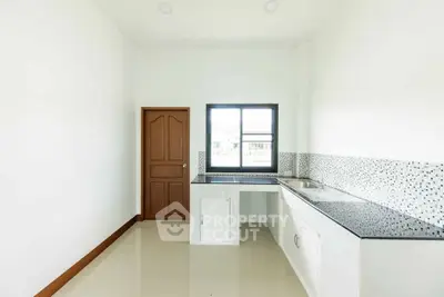 Modern minimalist kitchen with sleek countertops and ample natural light.