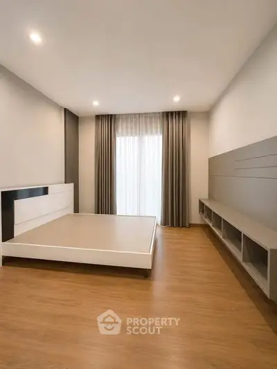 Spacious modern bedroom with wooden flooring and large window