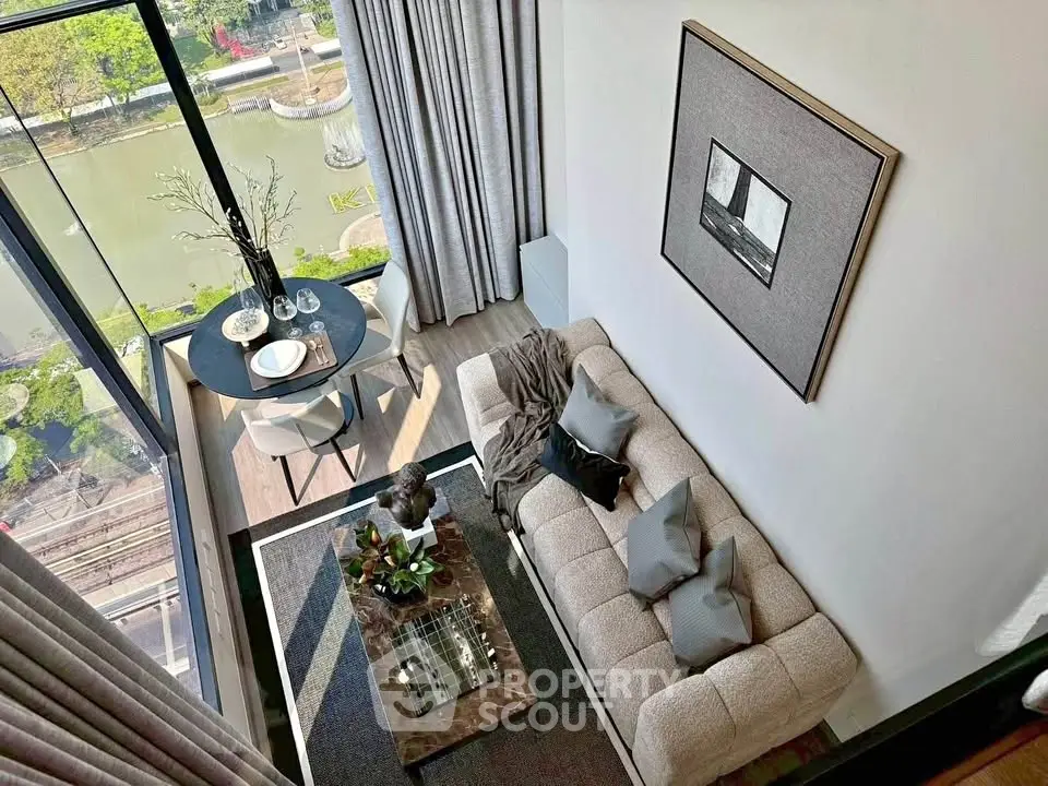 Stylish modern living room with large windows offering a scenic river view, elegant decor, and cozy seating area.