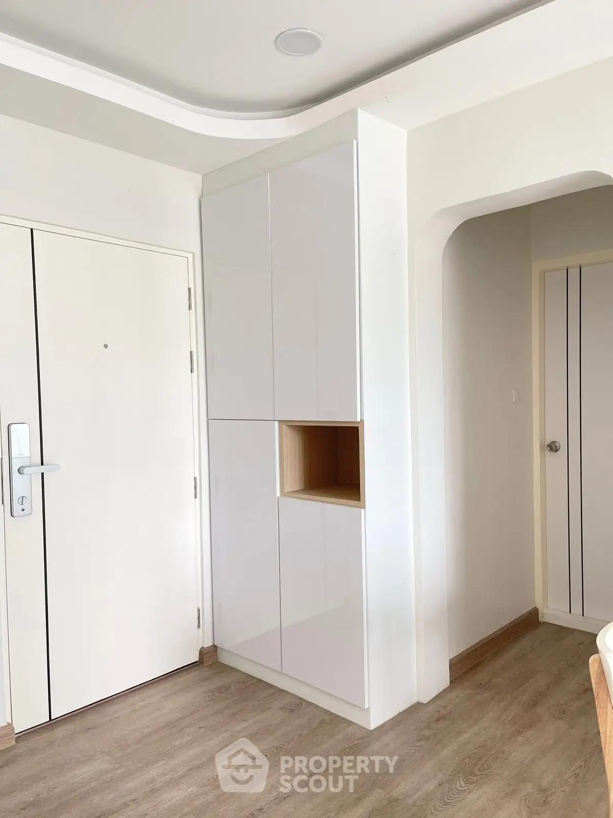 Modern entryway with sleek white cabinetry and wooden flooring