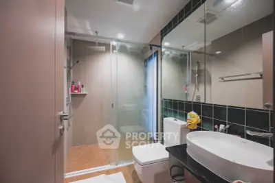 Modern bathroom with glass shower and sleek fixtures in contemporary apartment.