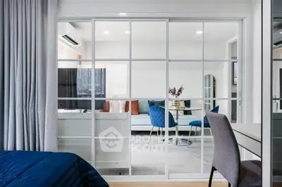 Modern open-plan living room with glass partition and stylish furniture.