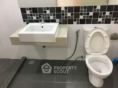 Modern bathroom with sleek sink and toilet, featuring stylish tile design.