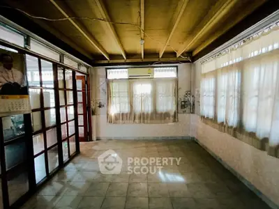 Spacious living room with tiled floor and large windows, featuring an air conditioning unit for comfort.