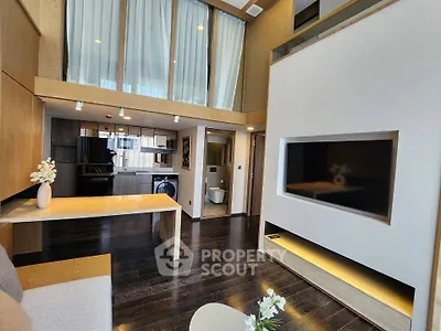 Modern living room with high ceilings and open layout, featuring sleek wooden floors and contemporary decor.