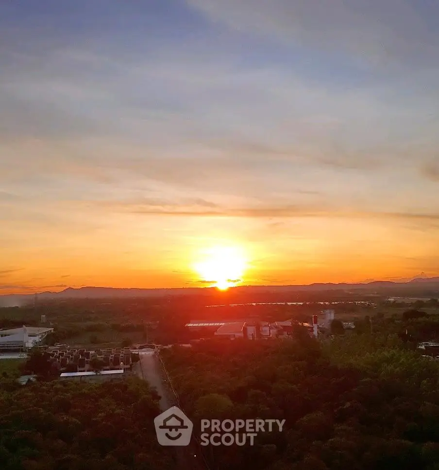 Stunning sunset view from a high vantage point overlooking lush greenery and distant mountains.