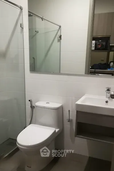 Modern bathroom with glass shower and sleek fixtures in contemporary apartment.