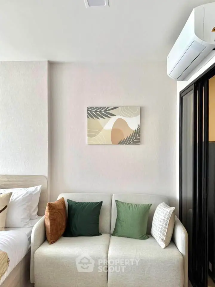 Cozy living room with modern decor and air conditioning, featuring a comfortable sofa and stylish wall art.