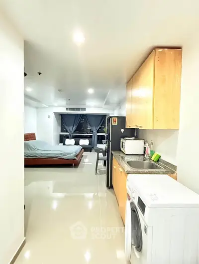 Modern studio apartment with open kitchen and cozy bedroom area, featuring sleek appliances and stylish decor.