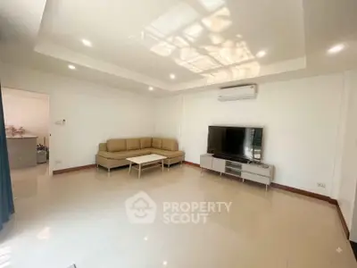 Spacious living room with modern sofa and large TV, perfect for relaxation.