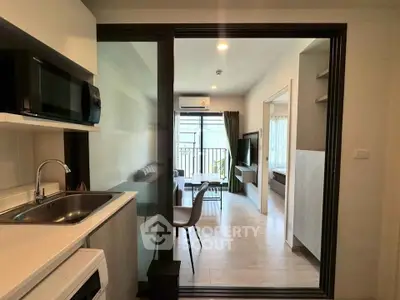 Modern apartment interior with open kitchen and cozy living room leading to a balcony.