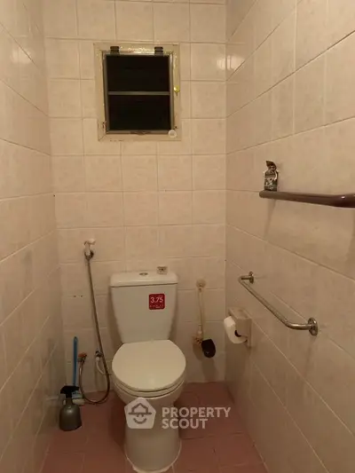 Compact bathroom with tiled walls and basic fixtures, featuring a small window for ventilation.