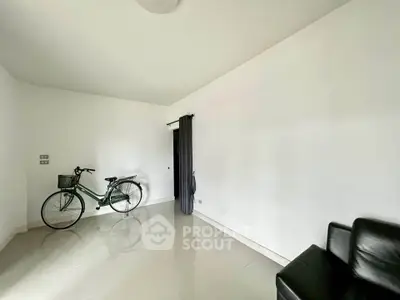 Minimalist room with bicycle and black leather chair, white walls and glossy floor.