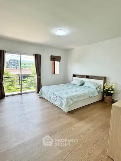 Spacious bedroom with large window and balcony access, offering a serene view and abundant natural light.