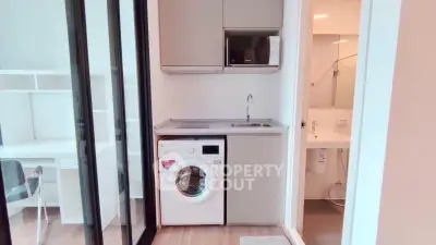 Modern compact kitchen with washing machine and microwave in sleek apartment