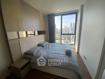 Modern bedroom with city view, featuring a cozy bed and large window for natural light.