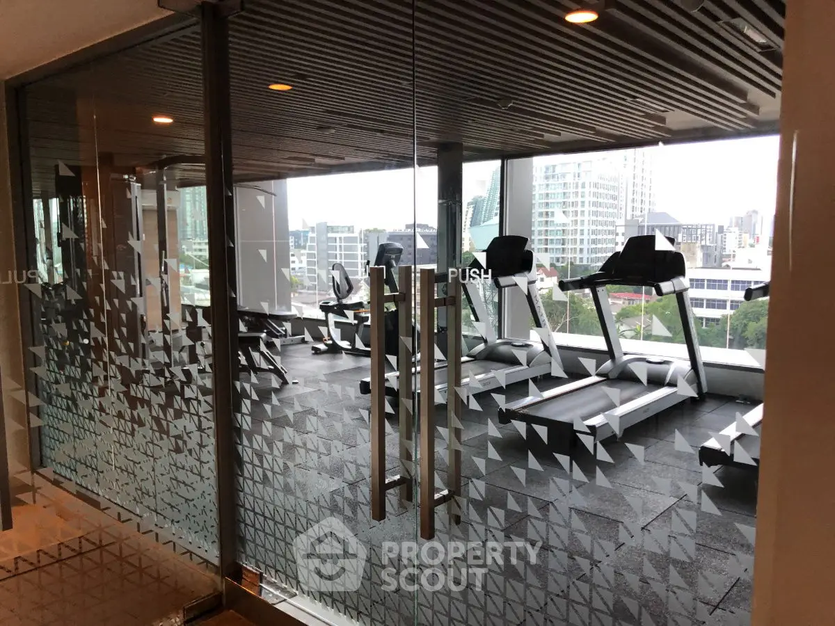 Modern gym with city view and state-of-the-art equipment in luxury building.