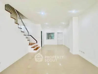 Spacious modern living room with sleek staircase and glossy tiled floors