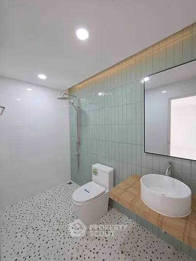 Modern bathroom with sleek design, featuring a rain shower, stylish sink, and elegant tile work.