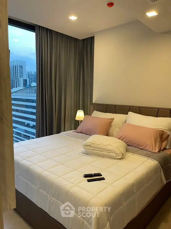 Modern bedroom with city view, featuring cozy bed and ambient lighting in a high-rise apartment.