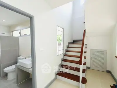 Modern staircase with adjacent bathroom in a bright, minimalist home interior.