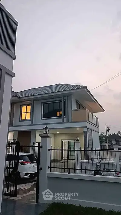 Modern two-story house with sleek design and gated entrance at dusk.