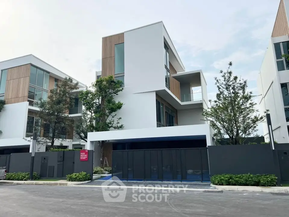 Modern multi-story house with sleek design and large windows in a serene neighborhood.
