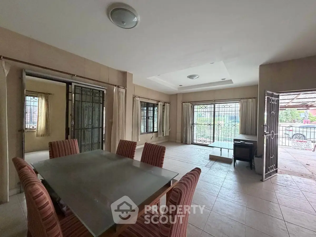 Spacious dining area with glass table and striped chairs, opening to a bright patio.
