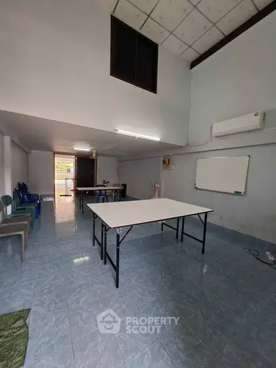 Spacious room with tiled floor, folding table, and air conditioning, ideal for meetings or classes.