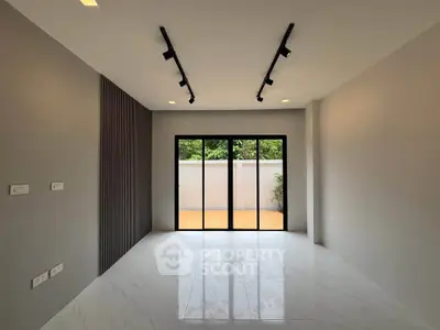 Spacious modern living room with large windows and sleek track lighting.