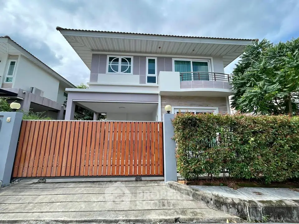 Modern two-story house with wooden gate and lush greenery