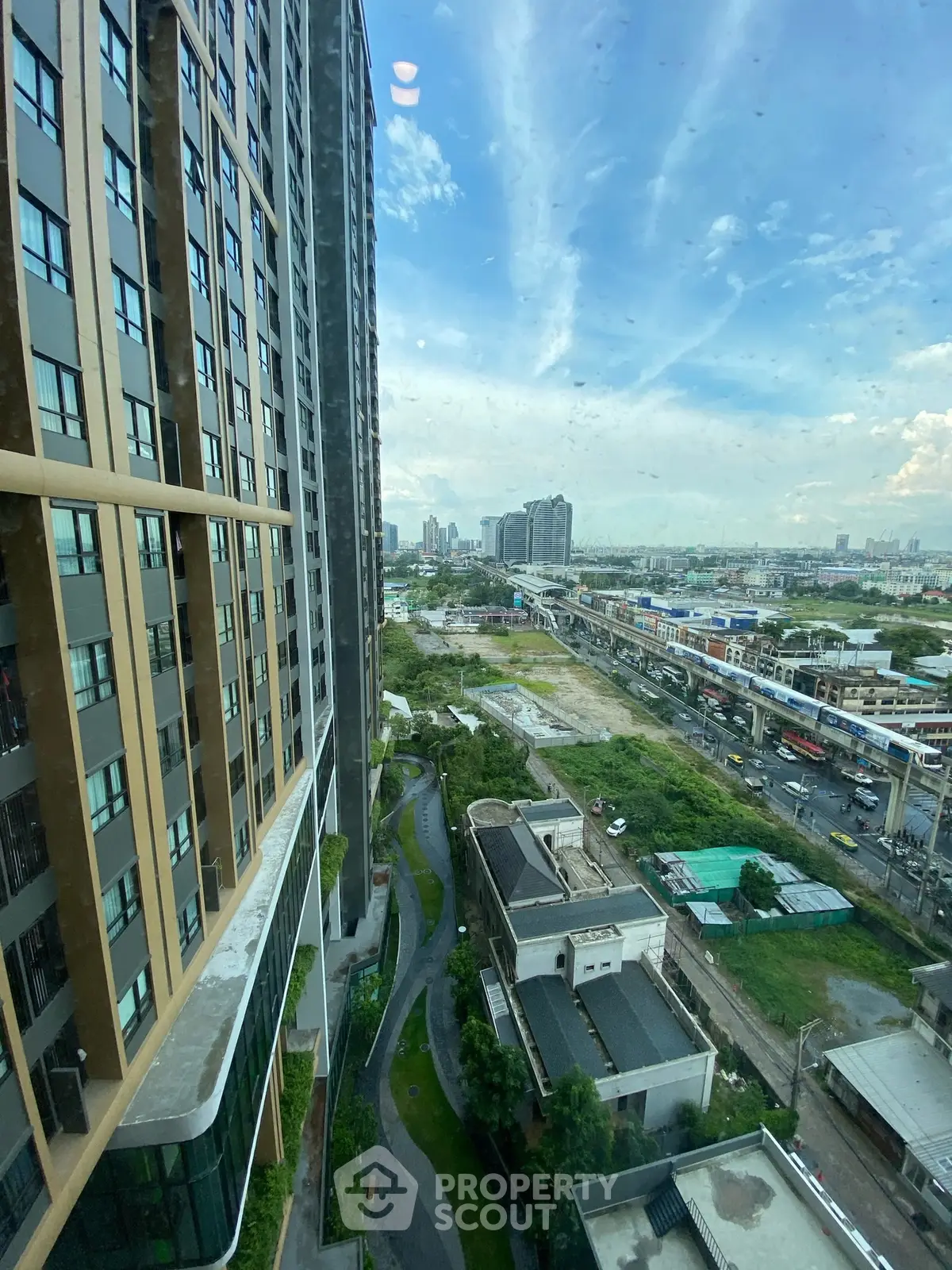 Stunning cityscape view from high-rise building with lush greenery and urban skyline.