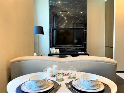 Elegant living room with modern decor and dining setup, featuring a sleek TV and stylish lighting.