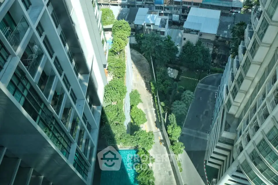 Stunning aerial view of modern high-rise buildings with lush greenery and pool, offering urban luxury living.