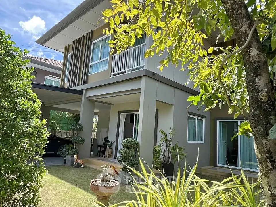 Modern two-story house with lush garden and carport, showcasing contemporary architecture and serene outdoor space.
