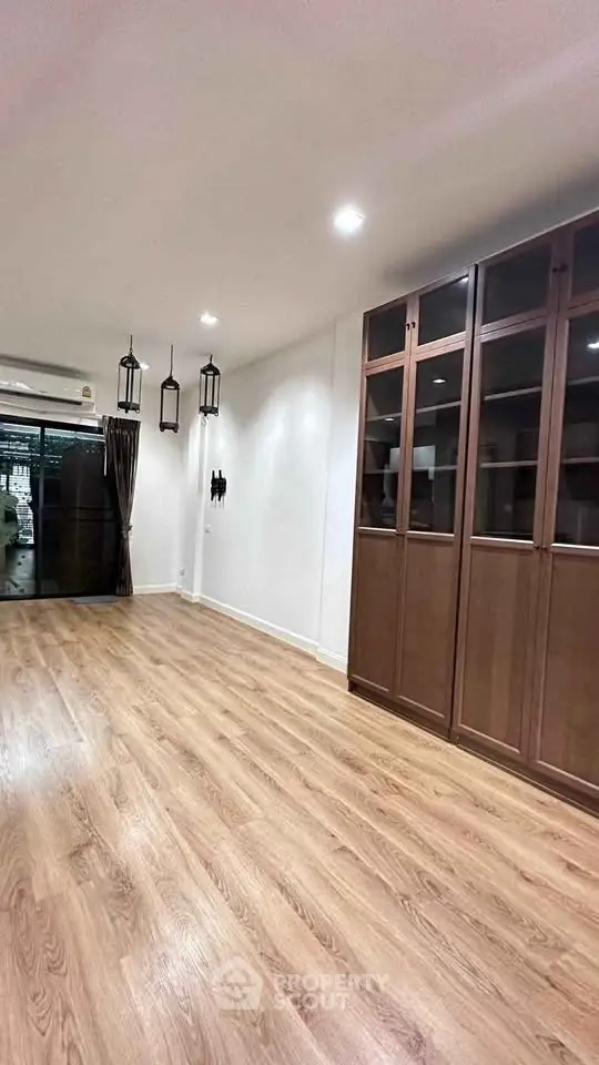 Spacious living room with elegant wooden flooring and built-in cabinets.