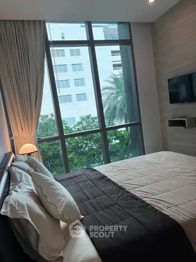 Luxurious bedroom with floor-to-ceiling windows and modern decor, offering a serene garden view.