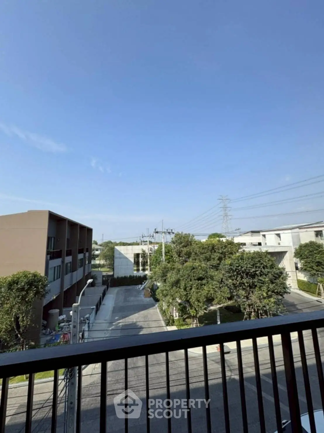 Modern urban view from balcony with clear blue sky and residential buildings.