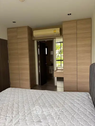 Modern bedroom with built-in wardrobes and air conditioning, featuring a glimpse into an ensuite bathroom.