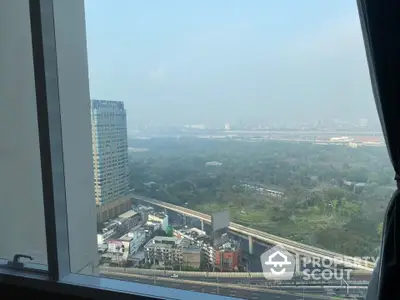 Stunning cityscape view from high-rise apartment window overlooking lush greenery and urban skyline.