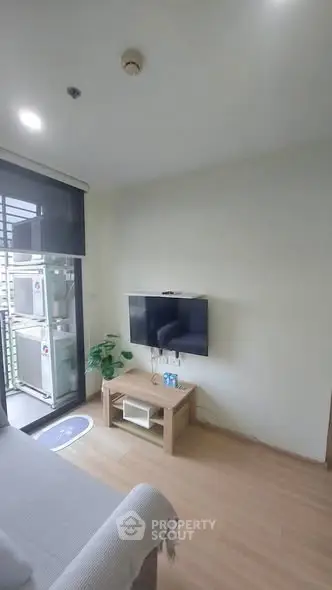 Modern living room with wall-mounted TV and balcony access in a stylish apartment.